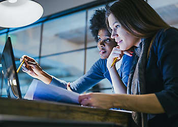 Two women at the computer working on a project