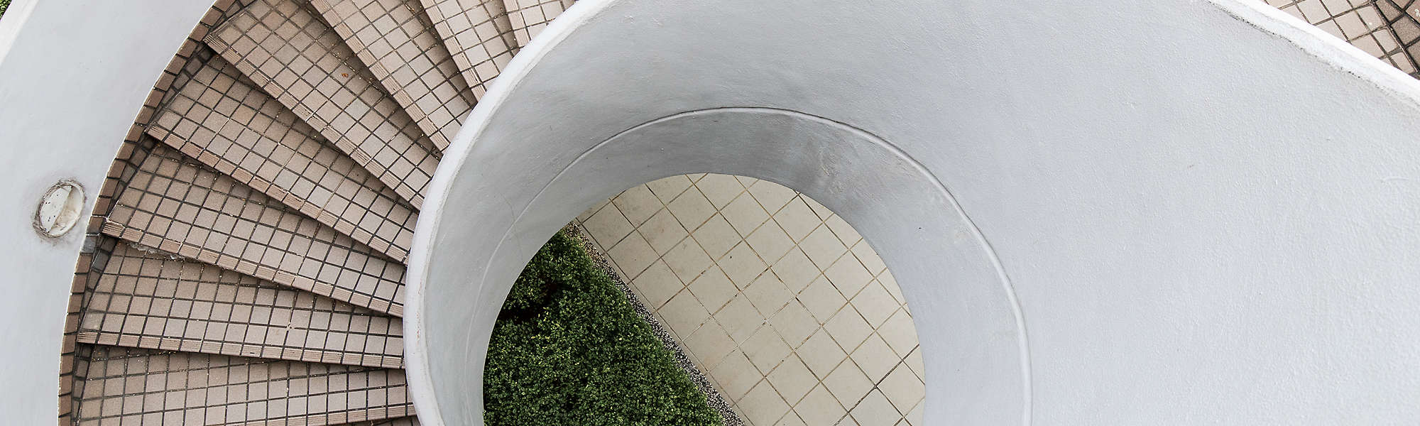 Overhead view of an empty outdoor spiral staircase with white tile.