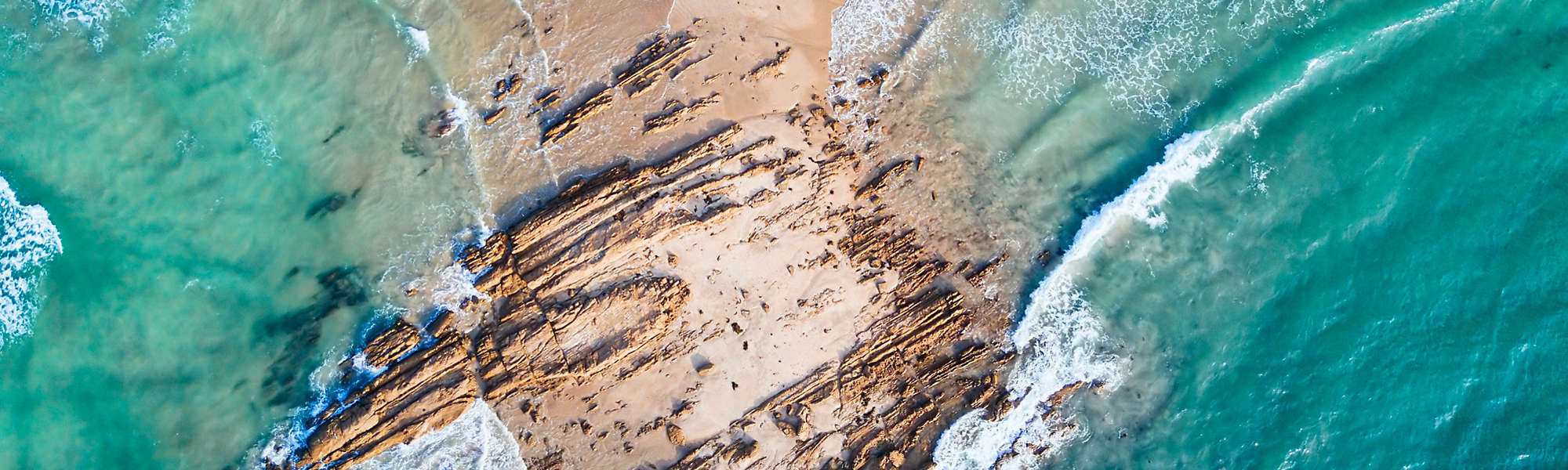 Aerial view of the ocean waves coming in on a rocky beach.